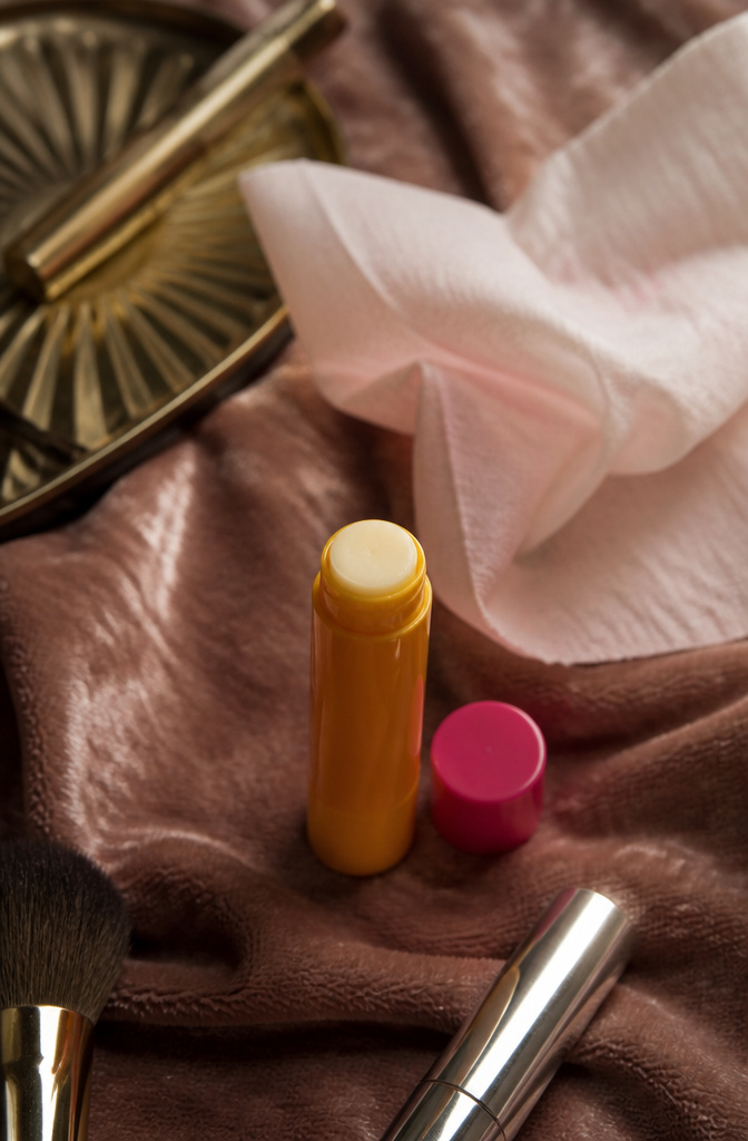 Burt's Bees Ultra Conditioning Lip Balm on velvet fabric with a cleansing towelette.